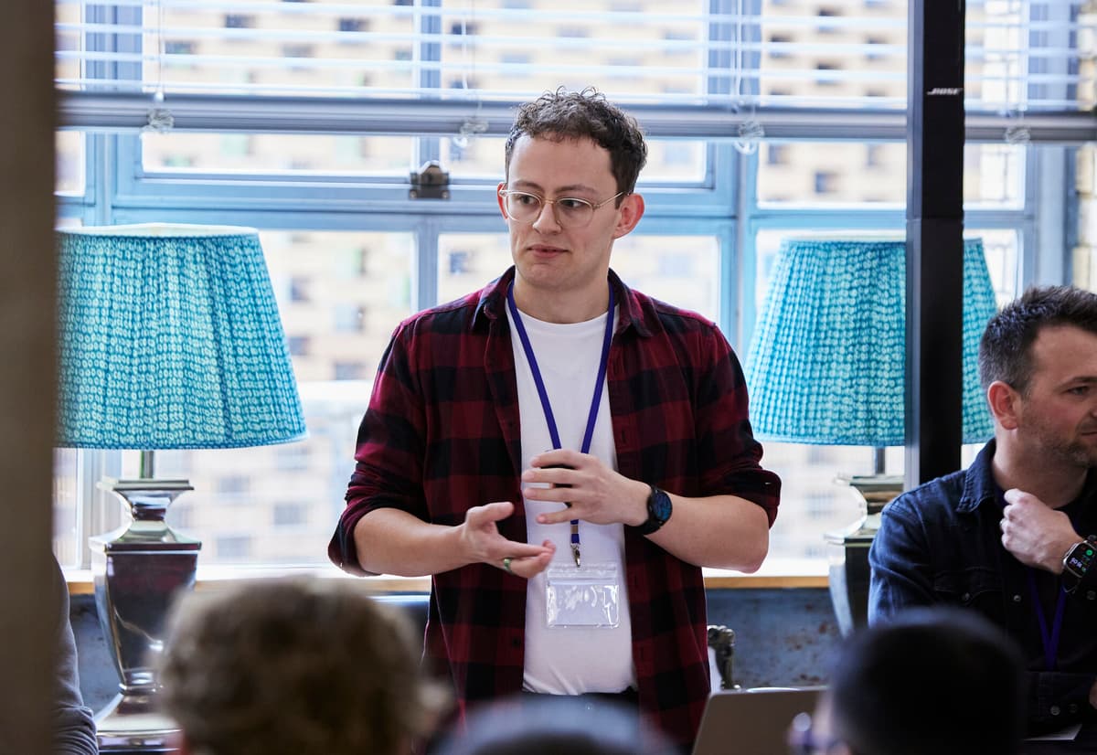 Aaron addressing the room, backlit by large windows